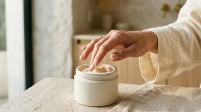 A fingertip dipping into a rich unbranded luxury moisturizer jar